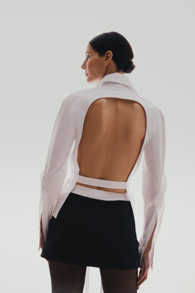 The shirt is white with an open back