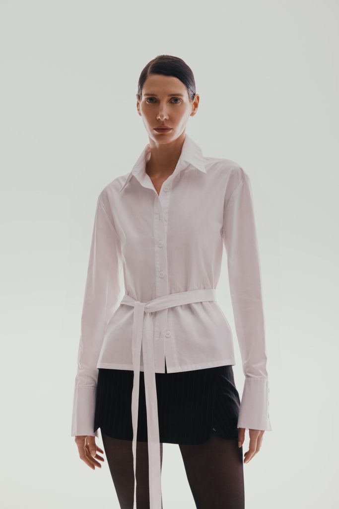 The shirt is white with an open back